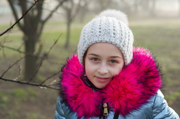 Zbliżenie portret pięknej dziewięcioletniej dziewczynki w jesiennym parku. 9-letnia dziewczyna w kapeluszu i niebieskiej kurtce. - Zdjęcie, obraz