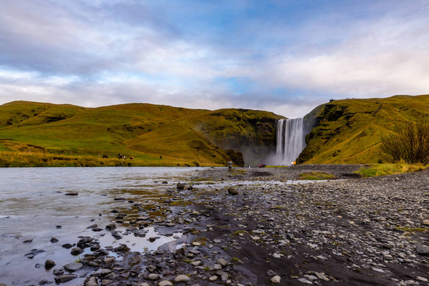 Skogafoss waterfall seen from afar with unrecognisable visitors, - Photo, Image