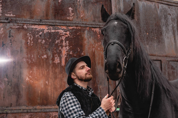 Portrait d'un gars avec un chapeau et un cheval noir
. - Photo, image