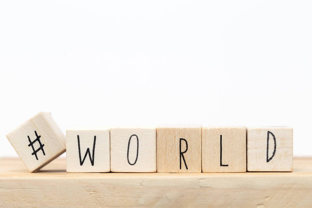 Cubos de madeira com uma hashtag e a palavra Mundo, conceito de mídia social perto de fundo branco
 - Foto, Imagem