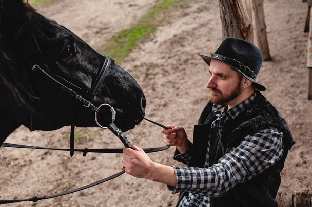 Porträt eines Mannes mit Hut und schwarzem Pferd. - Foto, Bild
