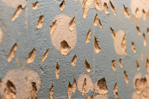 Een betegelde muur. Voorbereiding op reparatie. Gebroken en gruizig oppervlak. Ruwe textuur van blauwe kleur met bruine vlekken. - Foto, afbeelding