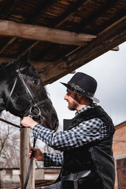 Portrét chlapa v klobouku s černým koněm. - Fotografie, Obrázek