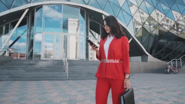 Confident business woman in formal suit is using her mobile phone outdoors - Imágenes, Vídeo
