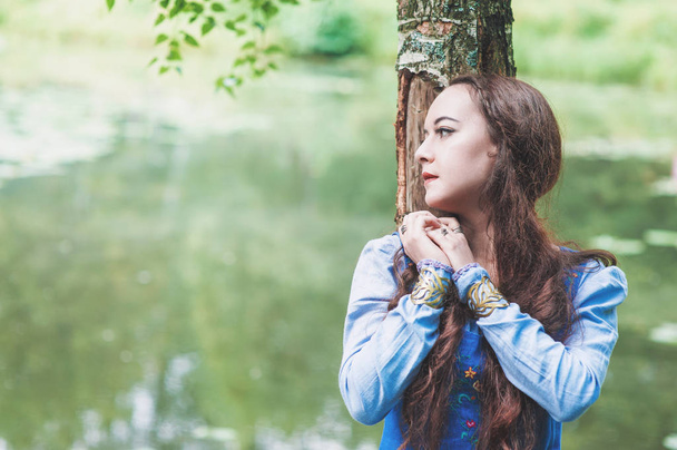 Beautiful woman in blue medieval dress near river - Photo, image