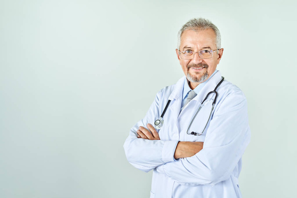 Fröhlich reifer Arzt posiert und lächelt in Kamera, Gesundheitswesen und Medizin. - Foto, Bild
