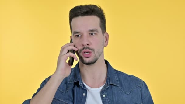 Portrait of Upset Young Man getting Angry on Smartphone, Yellow Background - Imágenes, Vídeo