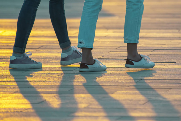 πόδια των ανθρώπων που περπατούν στο ηλιοβασίλεμα. Αναψυχή και αναψυχή στο  - Φωτογραφία, εικόνα