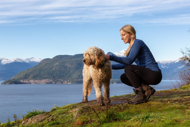Adventurous Girl Hiking on top of a Mountain with a dog - Valokuva, kuva