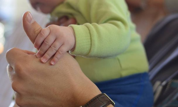 Baby's hand holding father's thumb.  - 写真・画像