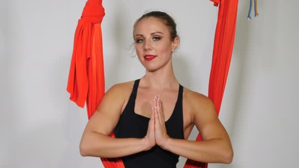 Wideo portret młodej, elastycznej kobiety sportowca spoczywa i koncentruje się z dłońmi zapiętymi w namaste pozycji rozciągającej mięśnie i rozwijającej elastyczność. Strzał na białym tle. 4k - Materiał filmowy, wideo