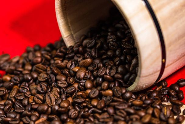 pražená kávová zrna v dřevěné kávové nádobě na červeném pozadí, t - Fotografie, Obrázek