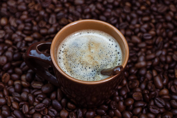 Koffiekop met gebrande koffiebonen op rode achtergrond, koffie c - Foto, afbeelding