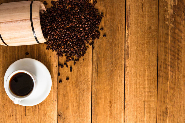 Bir fincan kahve, ahşap arka planda kavrulmuş kahve fasulyesi, kahve. - Fotoğraf, Görsel
