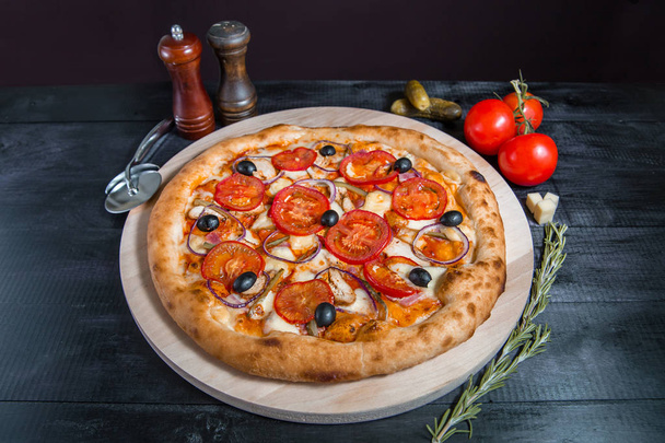 Rustic pizza with salami, mozzarella, fresh tomatoes, red onion, black olives and fresh basil. Home made pizza. - Фото, изображение