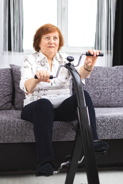 Seniorentraining zu Hause. Seniorin macht Sport zu Hause auf einem - Foto, Bild