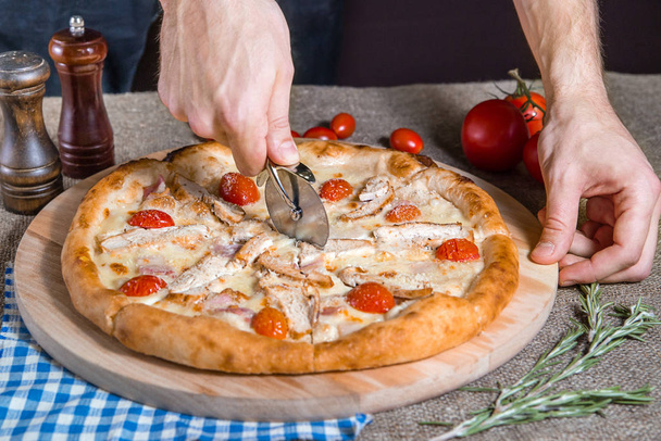 Pizza Cutter Pizza maison avec jambon, bacon, fromage, viande, tomates
 - Photo, image