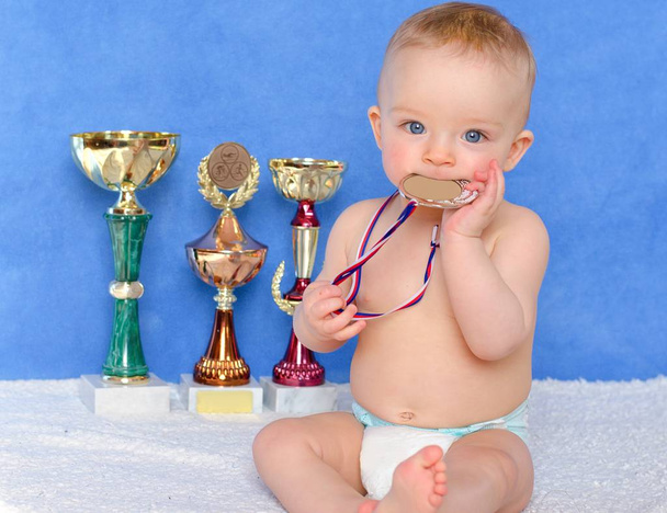 Little winner. Cute toddler wearing diaper and holding a medal.  - Фото, зображення