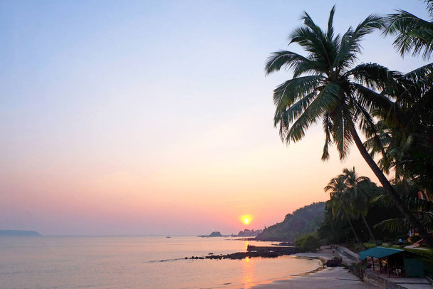 Uma baía tropical com um mar calmo e palmeiras brilhando vermelho no
 - Foto, Imagem