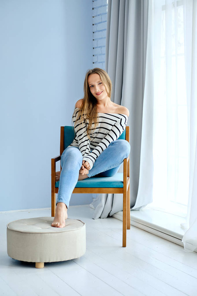 Girl sitting in armchair in bright livingroom - Fotoğraf, Görsel