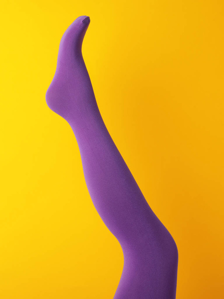 Leg mannequin in purple tights on yellow background - Foto, imagen
