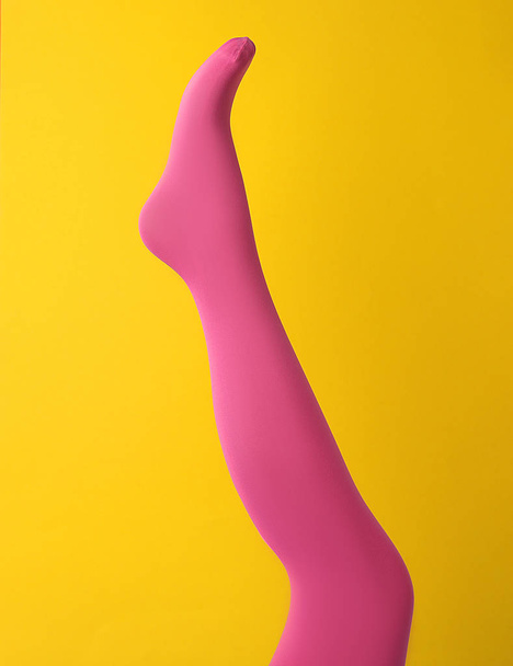 Leg mannequin in pink tights on yellow background - Φωτογραφία, εικόνα
