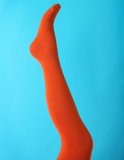 Leg mannequin in orange tights on blue background - Valokuva, kuva