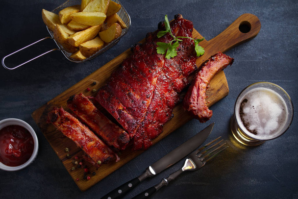 Rack of ribs, barbecue sauce, fries and light beer. Overhead horizontal image - Foto, Imagem