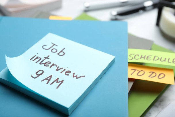 Reminder note about job interview and stationery on table, closeup - 写真・画像