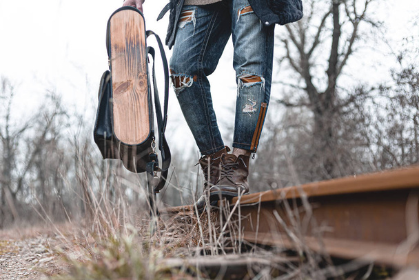 鉄道の上にスエードの秋のブーツを着た男。ハイキング、旅行の実用的な服、靴の概念. - 写真・画像