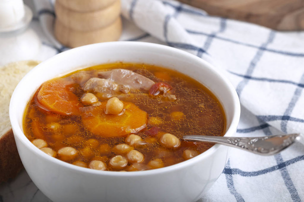 Sopa con pollo, guisantes, tomate y zanahorias en rodajas. Sopa caliente sabrosa
. - Foto, Imagen