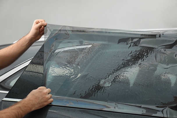 Worker tinting car window with foil in workshop, closeup - Foto, Imagen
