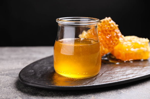 Tasty aromatic honey and combs on grey table - Fotoğraf, Görsel