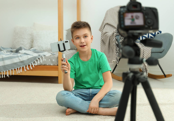 Cute little blogger with phone and selfie stick recording video at home - Valokuva, kuva
