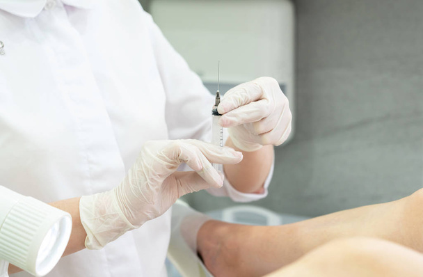 Ginecologista segurando seringa pronto para fazer uma injeção para o paciente em cadeira de ginecologia
 - Foto, Imagem