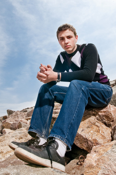 Young man on the rocks in clouds - Foto, imagen