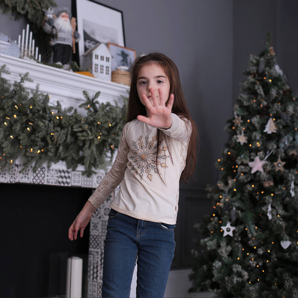 Krásná dívka s dlouhými tmavými vlasy se poflakuje se sušenkami na novoroční bokeh světla na zdobené vánoční stromeček - Fotografie, Obrázek