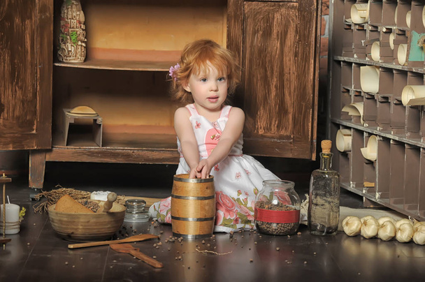 red-haired girl sitting plays in the vintage kitchen - Φωτογραφία, εικόνα