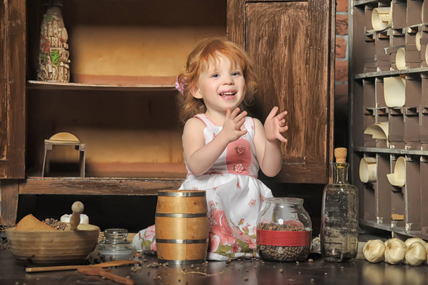 red-haired girl sitting plays in the vintage kitchen - Φωτογραφία, εικόνα