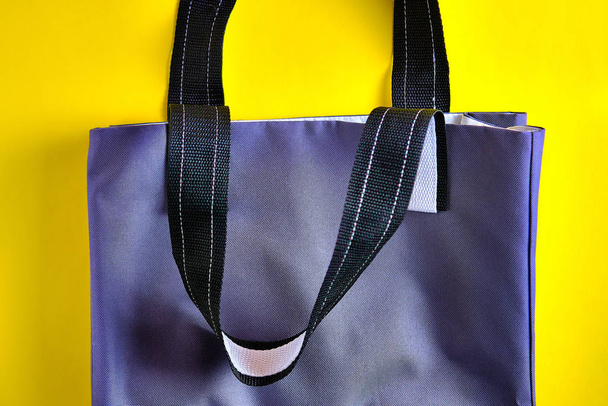 Vista lateral de la bolsa textil gris hecha con materiales naturales sobre el fondo amarillo brillante. Concepto de estilo de vida de cero residuos, protección del medio ambiente, Día de la Tierra
. - Foto, Imagen