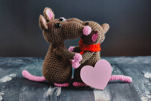Ručně vyrobené krysy amigurumi se objímají. Růžové srdce stojí blízko. Valentýn, 14. února, láska, koncept vztahů - Fotografie, Obrázek