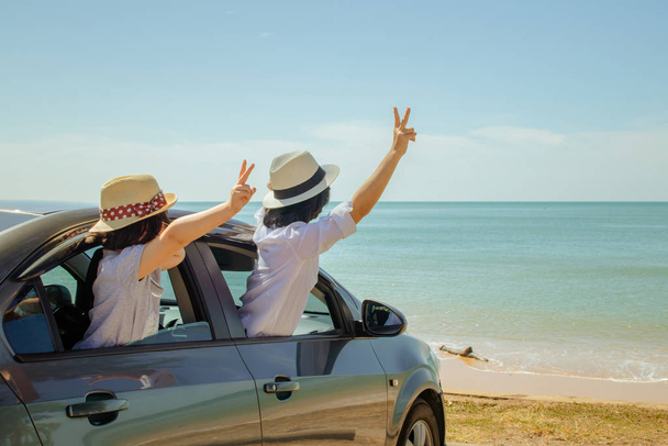 Summer Vacation and Car Trip Concept: Perhe auto matka merellä, Nainen ja lapsi iloinen nostamalla kätensä ylös ja tunne onnea hopea auton merimaisema taustalla
. - Valokuva, kuva
