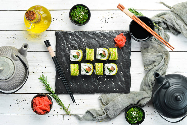 Sushi rolka s avokádem, lososem a cibulí. Volné místo pro text. Tradiční japonská kuchyně. Horní pohled. Rustikální styl. - Fotografie, Obrázek