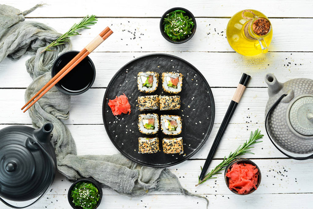 Sushi roll with sesame, Philadelphia cheese, salmon, avocado. Japanese Traditional Cuisine. Top view. Rustic style. - Valokuva, kuva