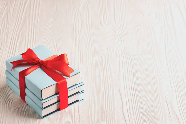 Books tied with ribbon on a wooden background with copy space: concept of donating books - Photo, Image