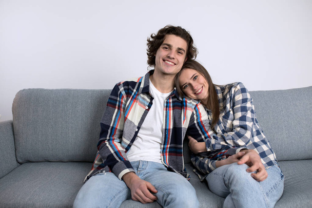 Jeune couple détendu souriant tout en posant sur le canapé
 - Photo, image