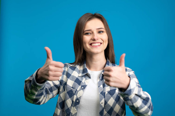 Front view of excited girl showing thumbs up isolated on blue background - Foto, Imagem