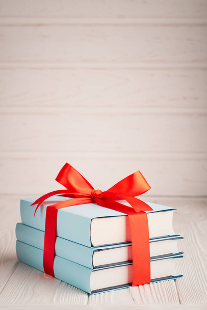A vertical shot of a book tied with ribbon with place for text: the concept of a good book is a good gift - Foto, imagen