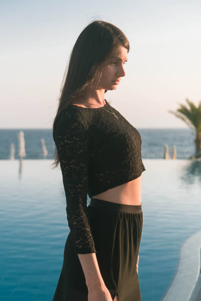 young fashion beautifull woman walking near the pool at sunset - Photo, Image