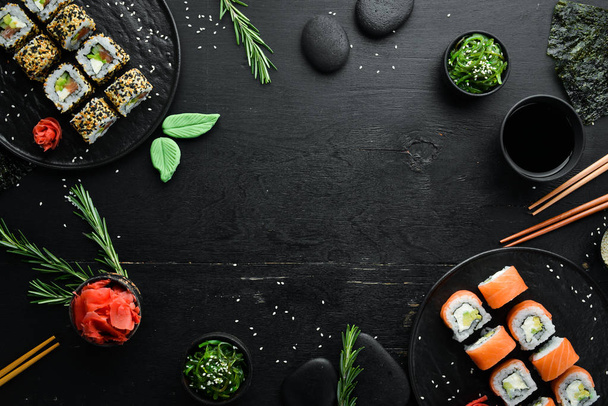 Set of sushi rolls with ginger, wasabi and soy sauce on a black stone background. Japanese Traditional Cuisine. Top view. Rustic style. - Photo, image